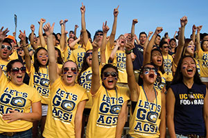 A crowd of students wearing yellow Go Ags! shirts rallies the team at a UC Davis football game