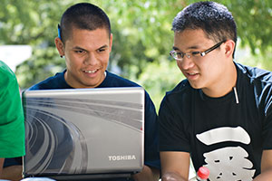 Two male students viewing a laptop on the UC Davis Quad