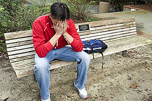 A distraught student sits on a bench