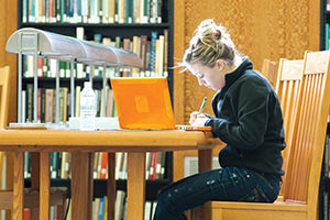 A female student working on her laptop in a Shields Library study room