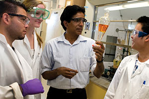 A professor and three students investigate the contents of a beaker in the chemistry department