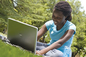 A female student using a laptop on the UC Davis Quad