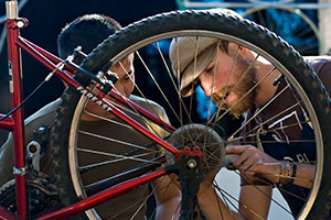 A student employee at a local bike shop helps a customer repair his bicylce.